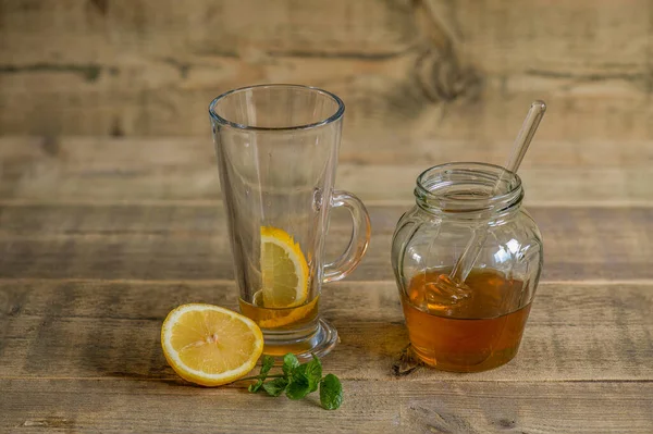 Tahta masadaki bal ve limon yatıştırıcı bir içecek olarak suyla karıştırılmaya hazır..