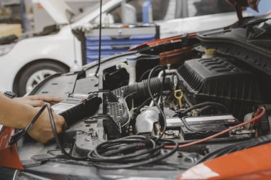 Bir tamirci tamir merkezindeki elektrik sistemini kontrol etmek için bir cihaz kullanır. Araç bakım kontrolü ve bakımı kavramı
