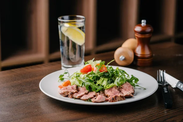 Salad with roast beef, arugula and cherry tomatoes. Serving in a cafe