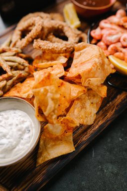 Deniz ürünleri birası aperatifleri. Kızarmış balık, patates kızartması, karides, kalamar halkası, limon dilimi, domates sosu ve tartar sosu.