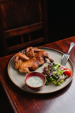 Kızarmış tavuk Tabaka, sarımsak sosu ve ahşap masada salata.