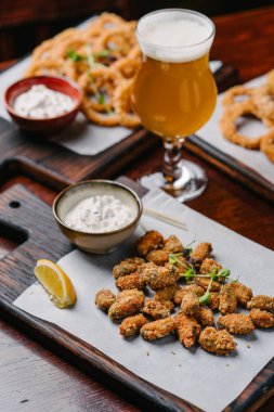 Bira takımı aperatifler kızarmış soğan halkaları, kalamar halkaları ve tartar soslu kızarmış midyeler ve bir bardak bira.