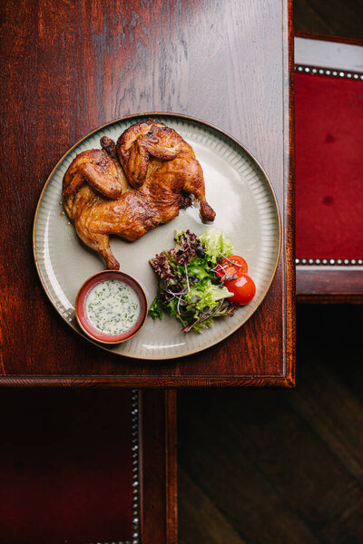 Жареный жареный цыпленок Табака с чесночным соусом и салатом на деревянном столе. Вид сверху