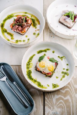 Smorrebrods, somon, yumurta, biftek, tatlı soğan, ringa, soğan, avokado ve kişniş soslu Danimarka sandviçi..