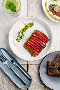 Gravlax, İskandinav kurutulmuş beyaz tabakta beyaz kremalı somon balığı. Üst görünüm