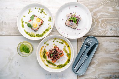 Smorrebrods, somon, yumurta, biftek, tatlı soğan, ringa, soğan, avokado ve kişniş soslu Danimarka sandviçi..