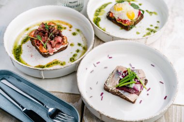 Smorrebrods, somon, yumurta, biftek, tatlı soğan, ringa, soğan, avokado ve kişniş soslu Danimarka sandviçi..