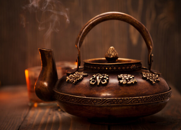 Antique iron hot tea pot on dark wooden background
