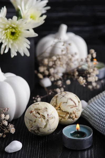 Herbal bath bombs. Fall decoration with white pumpkins and chrysanthemum on black wooden background. Still life autumnal greeting card and advertisment