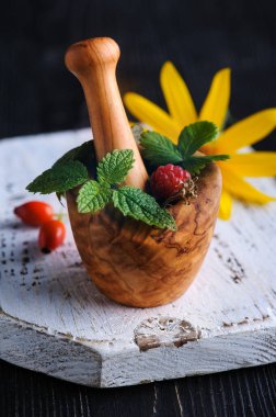 Taze eczacı organik aromatik otlar ve ahşap havan topuzlu böğürtlenler siyah arka planda. Nane, nane, kekik yaprakları. 