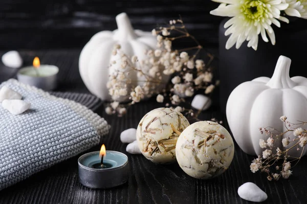 Herbal bath bombs. Fall decoration with white pumpkins and chrysanthemum on black wooden background. Still life autumnal greeting card and advertisment