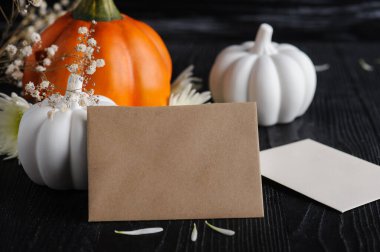 Üzerinde el işi zarfları, beyaz kâğıtlar ve siyah ahşap arka planda balkabakları olan maket kartı. Metinler için kopyalanmış bir hayat. Sonbahar tebrik kartı ve reklam kartı