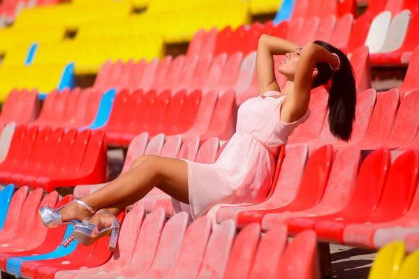 Aziatische model poseren in het stadion zitten op heldere stoelen — Stockfoto