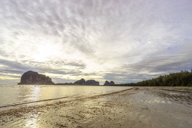 Sahilde gün batımı manzarası çok güzel. Işığın gölgesi denize düşüyor. Arka planda tepeler var. Pak Meng plajı, Trang, Tayland