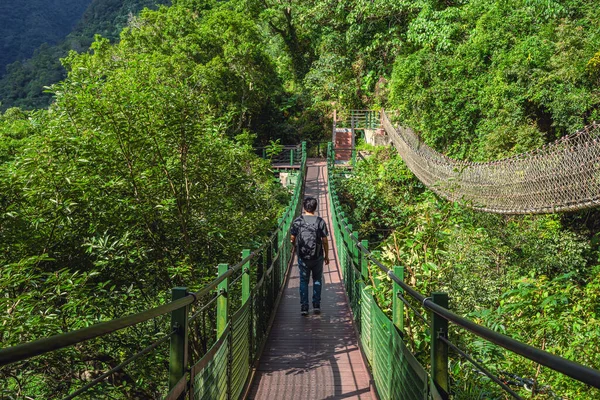 Tepeleri aşan yetişkin bir adam asma köprüsünü kullanarak sağ taraftaki diğer ipi kullanarak. (Taroko, Hualien, Tayvan).