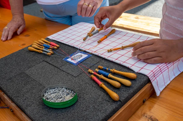 Hands making bobbin lace. Adult helps child learn craft. Colorful lace threads. Skill and creativity.