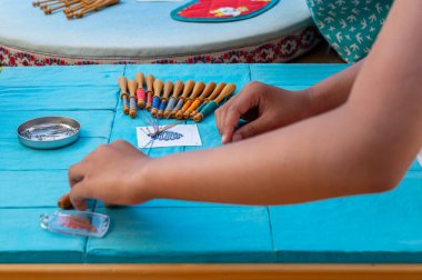 Hands of child making bobbin lace. Colorful lace threads. Skill and creativity.