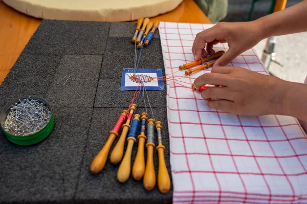 Hands of child making bobbin lace. Colorful lace threads. Skill and creativity.