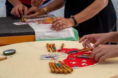 Hands of child and adult making bobbin lace. Colorful lace threads. Skill and creativity.