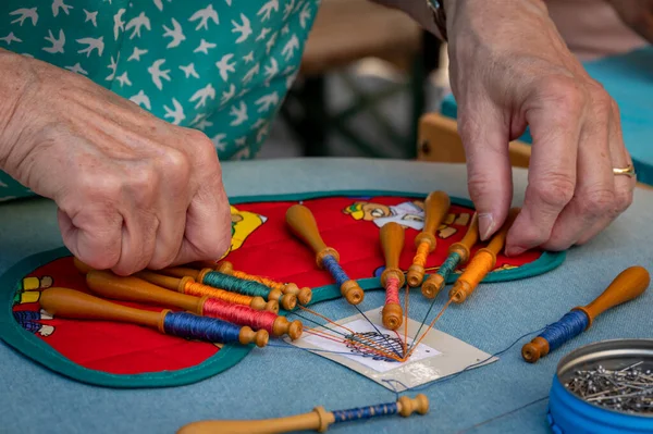 Hands of woman making bobbin lace. Colorful lace threads. Skill and creativity.