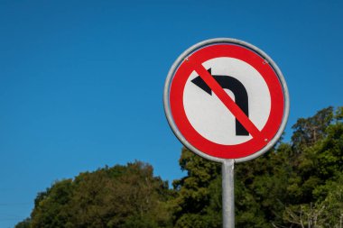 No left turn sign against blue sky. Traffic signs. Prohibited from turning left. Stop sign. Warning sign.