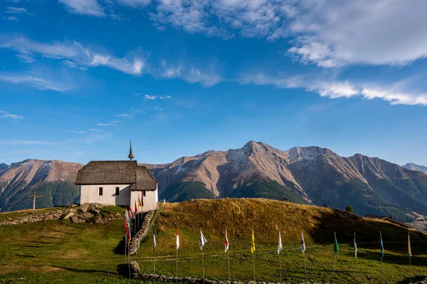 Landscape of church and mountains. Swiss Bettmeralp church with Swiss canton flags. Tranquil scene.