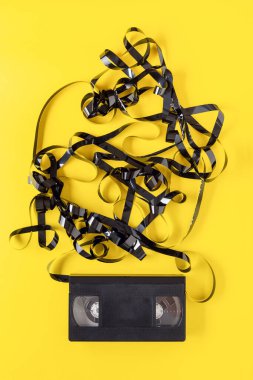 Sarı arka planda klasik VHS video kaseti. Kutunun dışındaki manyetik bant..