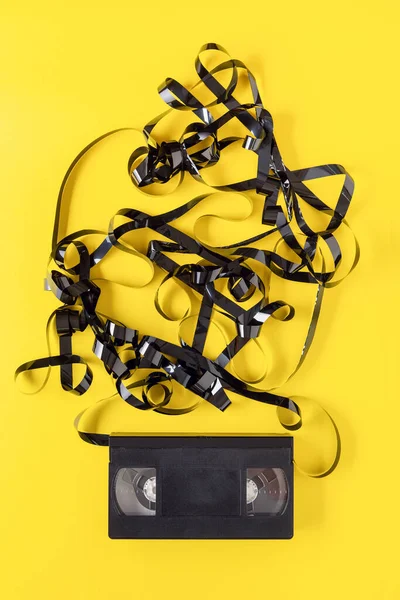 Sarı arka planda klasik VHS video kaseti. Kutunun dışındaki manyetik bant..