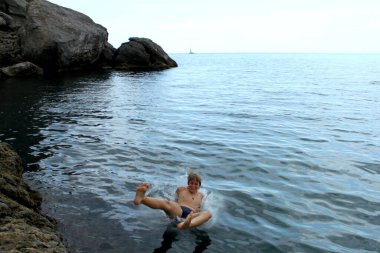 Uçurumdan denize atlayan genç bir çocuk.