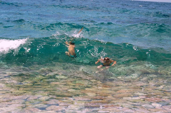 Children swimming in the transparent waves of the sea in summer