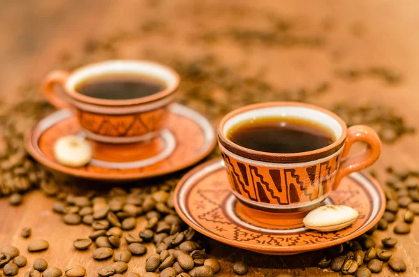 kahve kahve çekirdekleri ve ahşap bir masa üzerinde rustik bir görünüm ile Buhar olmayan buhar ile. bir fincan kahve kahve tane kurabiye bisküvi dahil ile birlikte
