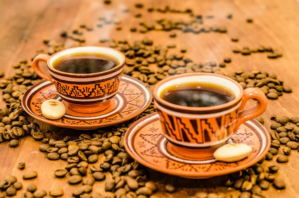 kahve kahve çekirdekleri ve ahşap bir masa üzerinde rustik bir görünüm ile Buhar olmayan buhar ile. bir fincan kahve kahve tane kurabiye bisküvi dahil ile birlikte