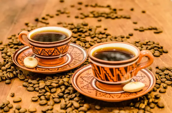 kahve kahve çekirdekleri ve ahşap bir masa üzerinde rustik bir görünüm ile Buhar olmayan buhar ile. bir fincan kahve kahve tane kurabiye bisküvi dahil ile birlikte