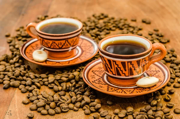 kahve kahve çekirdekleri ve ahşap bir masa üzerinde rustik bir görünüm ile Buhar olmayan buhar ile. bir fincan kahve kahve tane kurabiye bisküvi dahil ile birlikte