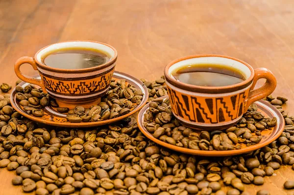 kahve kahve çekirdekleri ve ahşap bir masa üzerinde rustik bir görünüm ile Buhar olmayan buhar ile. bir fincan kahve kahve tane kurabiye bisküvi dahil ile birlikte