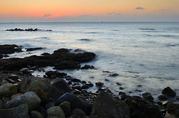 Sakin deniz ve gün batımı, sıcak bir kalıntı ile.