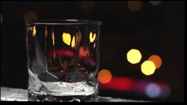 Bir yaz gecesinde arka planda şehir bokeh ile viski bardağına dökülen tek malt viski.