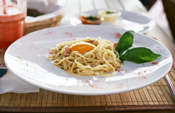 Läcker italiensk pasta carbonara på en vit platta Stockbild