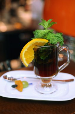 siyah çay, portakal, nane ve kuru meyveler beyaz bir plaka üzerinde