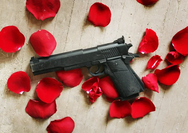 Pistolet noir pétales de roses rouges Image En Vente