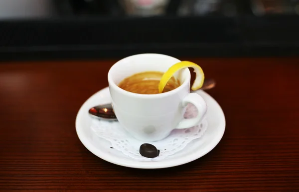 A white cup of coffee with a slice of lemon on a white saucer — Stock Photo, Image