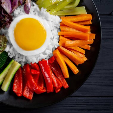 Close-up of a Korean dish, with a variety of appetizers with vegetables and eggs. Diet. pibimpap. Top view. Round plate.