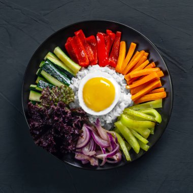 Close-up of a Korean dish, with a variety of appetizers with vegetables and eggs. Diet. pibimpap. Top view. Round plate.