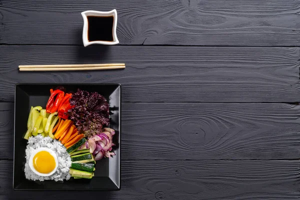 Close-up of a Korean dish, with a variety of appetizers with vegetables and eggs. Diet. pibimpap. Top view. Round plate.