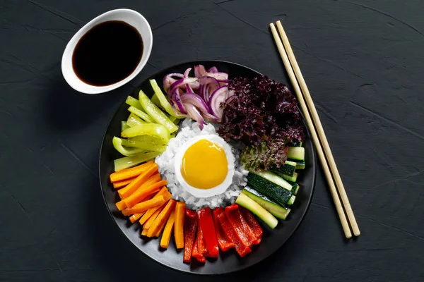 Close-up of a Korean dish, with a variety of appetizers with vegetables and eggs. Diet. pibimpap. Top view. Round plate.