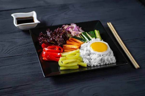 Close-up of a Korean dish, with a variety of appetizers with vegetables and eggs. Diet. pibimpap. Top view. Round plate.