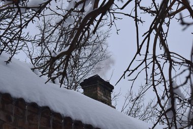 Kırsal bir evin tuğla bacası ve kışın içinden çıkan duman..