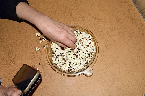 Mulher Comendo Pipoca Senta Mesa Com Telefone — Fotografia de Stock