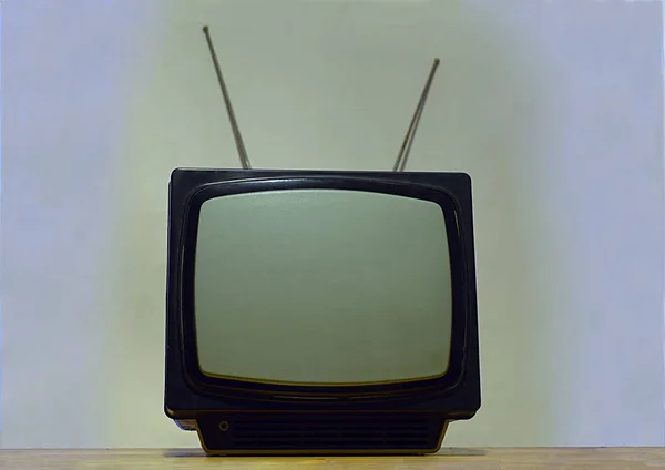 Old portable TV with antenna on a light background.
