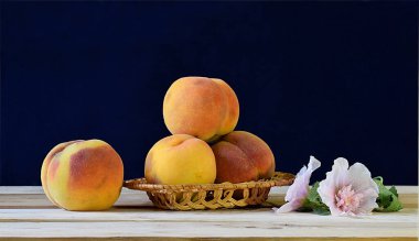 Hasır bir sepetin içinde olgun şeftaliler ve ahşap bir masanın üzerinde yumuşak bir çiçek..